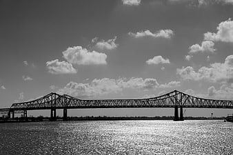 Black and white steel truss bridge over river with clouds