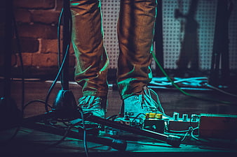 Musician's feet on guitar pedals with stage lighting