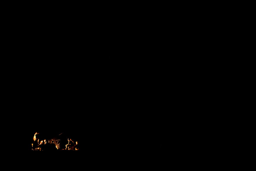 Group of People Sitting Around a Campfire at Night