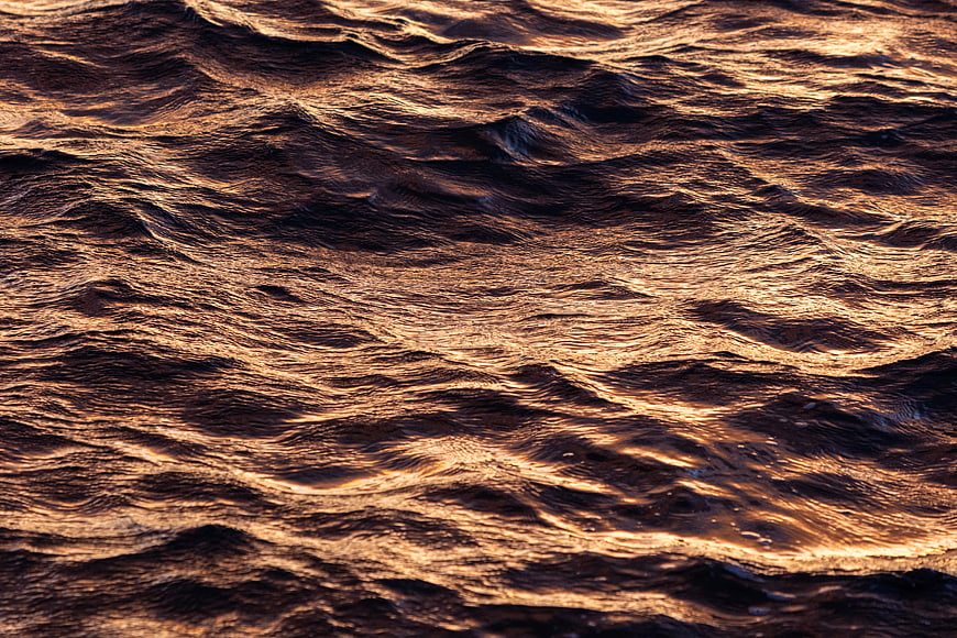 Golden Sunlight Reflecting on Dark Rippling Water Surface