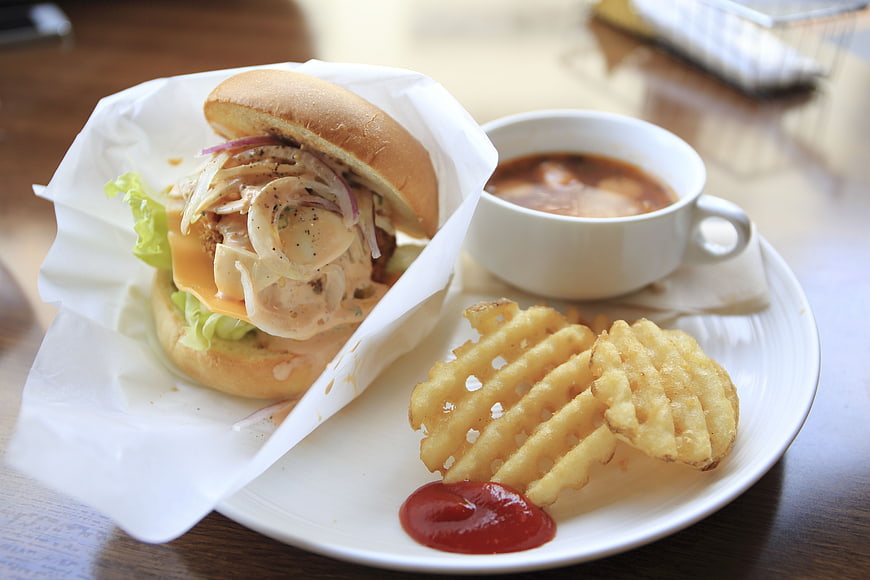 Delicious burger with waffle fries and soup on a plate