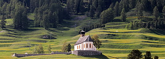 Alpine Chapel in Green Meadow with Forested Hills