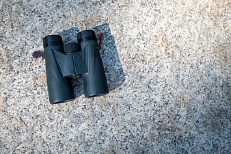 Black binoculars on textured granite rock surface