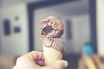 Hand holding chocolate ice cream cone with bite taken out