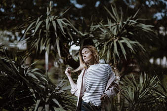 Serene woman with eyes closed in lush garden foliage