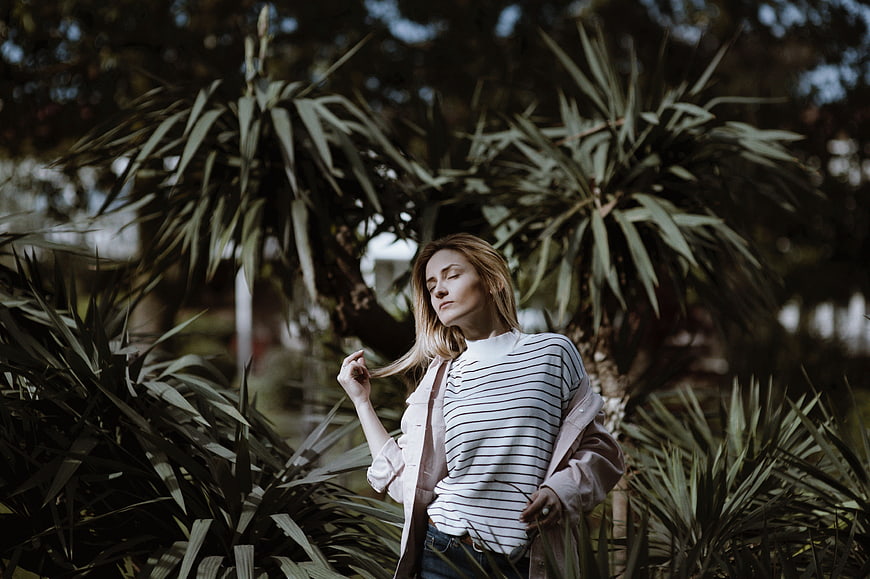 Serene woman with eyes closed in lush garden foliage
