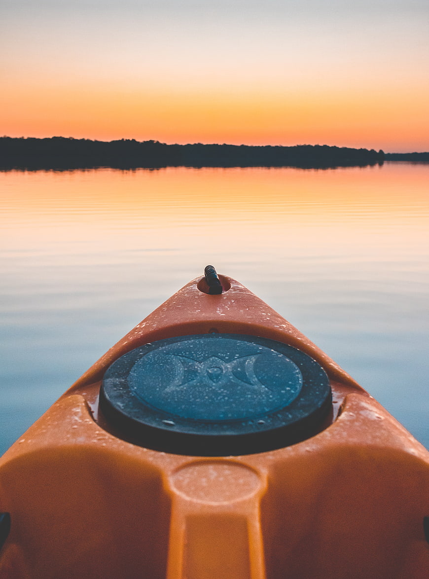 Orange Kayak Bow on Calm Lake at Sunset
