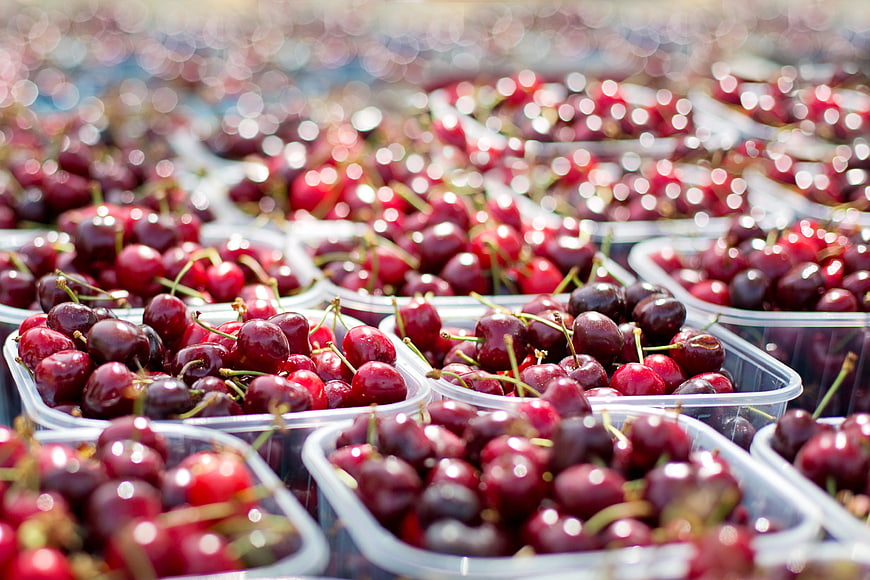 Fresh Ripe Cherries in Plastic Containers at Market