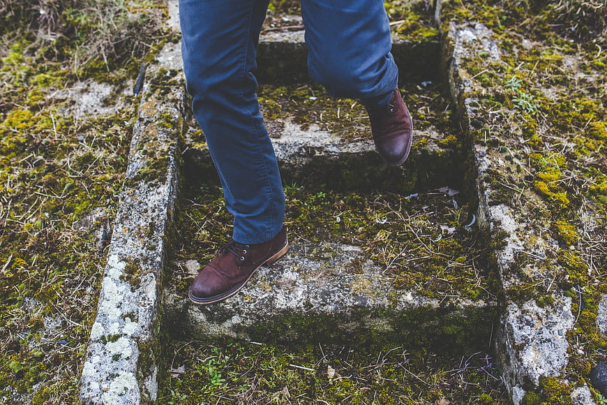 Man walking down mossy stone steps in nature