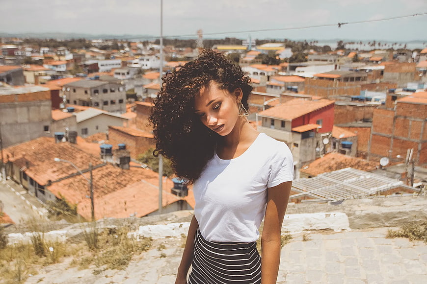 Woman with Curly Hair Looking Down Against Cityscape