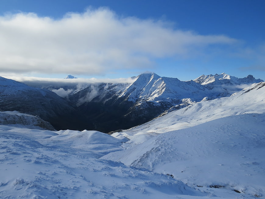 Snowy mountain landscape with clouds and blue sky