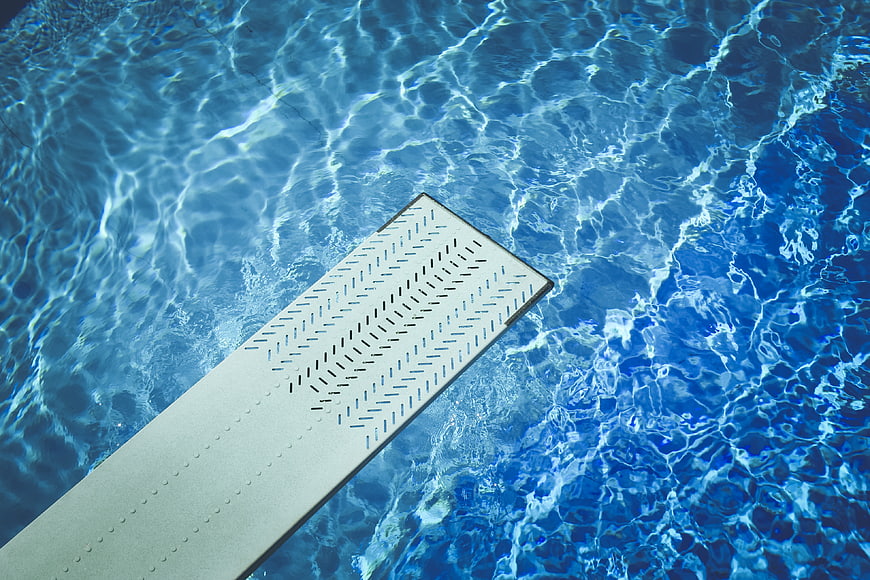 Top View of Diving Board Over Blue Pool Water