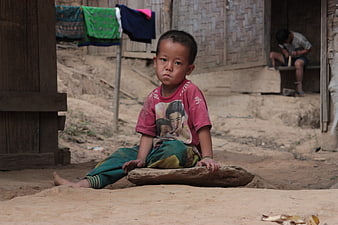 Portrait of a young boy sitting on a rock in a rural village