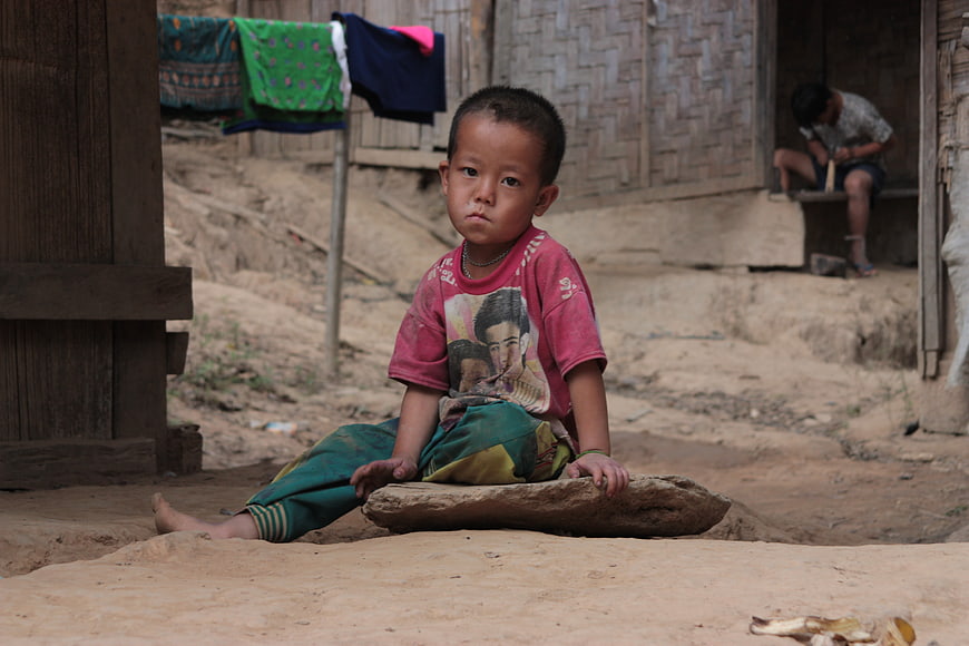 Portrait of a young boy sitting on a rock in a rural village