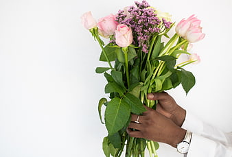 Hands holding pink roses and purple flowers bouquet