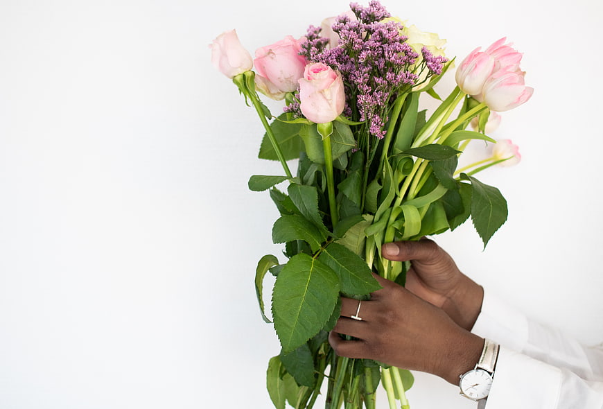 Hands holding pink roses and purple flowers bouquet