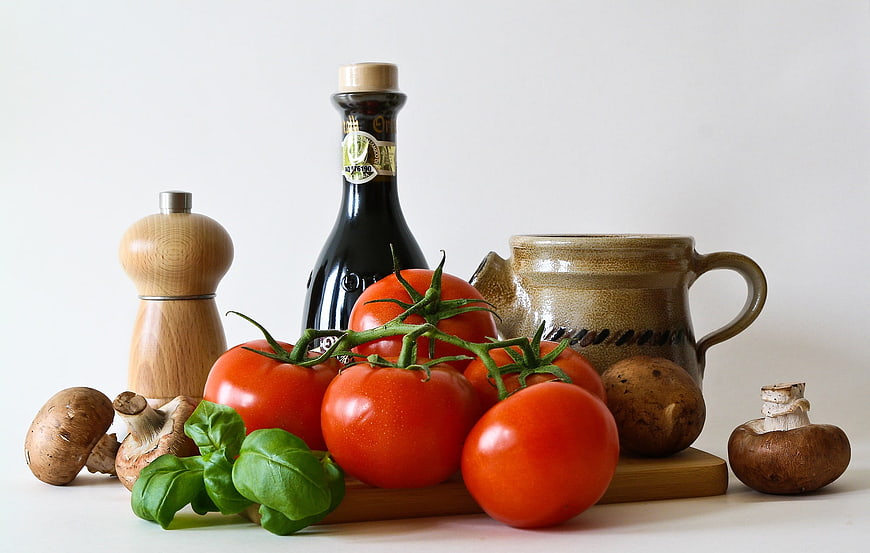 Fresh tomatoes, basil, mushrooms, and olive oil on white background