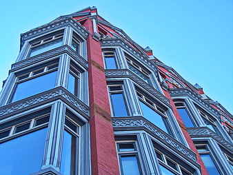 Low angle view of red brick building facade with blue sky