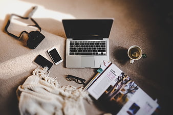 Flat lay of laptop, camera, and coffee on beige carpet