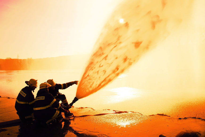 Firefighters Training With Powerful Water Jet At Sunset