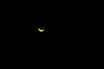 Crescent solar eclipse against a pitch-black night sky
