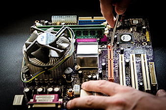 Technician repairing computer motherboard with screwdriver