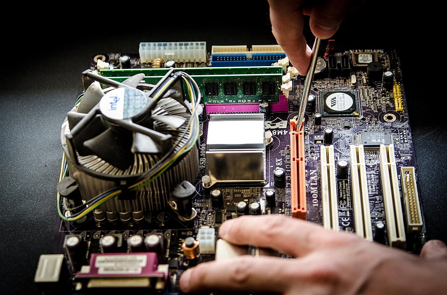 Technician repairing computer motherboard with screwdriver