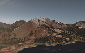 Rugged brown mountain landscape with snow patches and blue sky