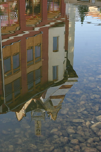 Colorful building reflection in clear water with pebbles