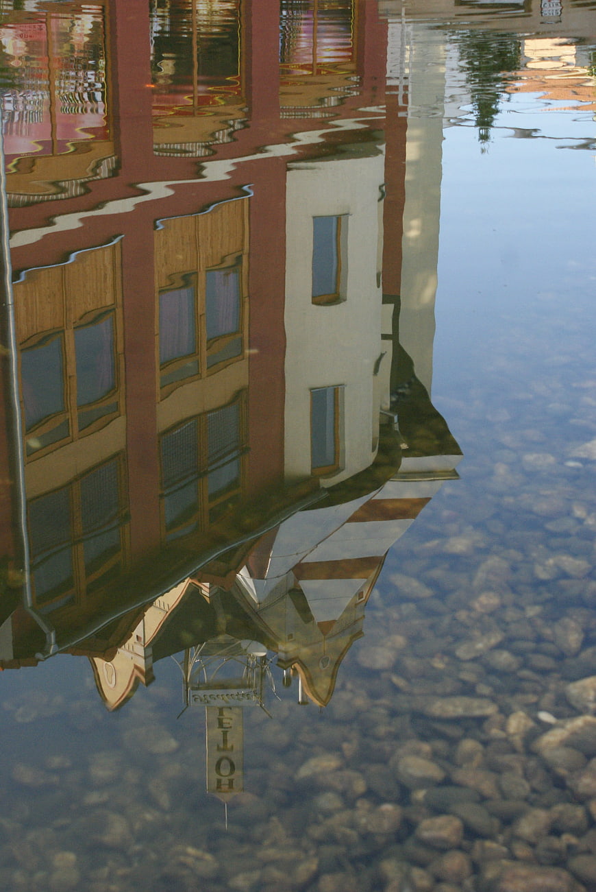 Colorful building reflection in clear water with pebbles
