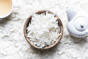 Top view of coconut flakes in wooden bowl with tea