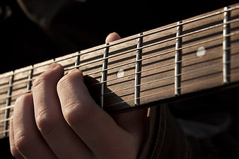 Close-up of hand playing acoustic guitar fretboard