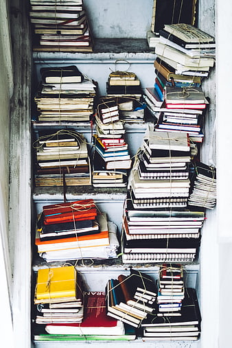 Stacks of old books and notebooks tied with twine on shelves