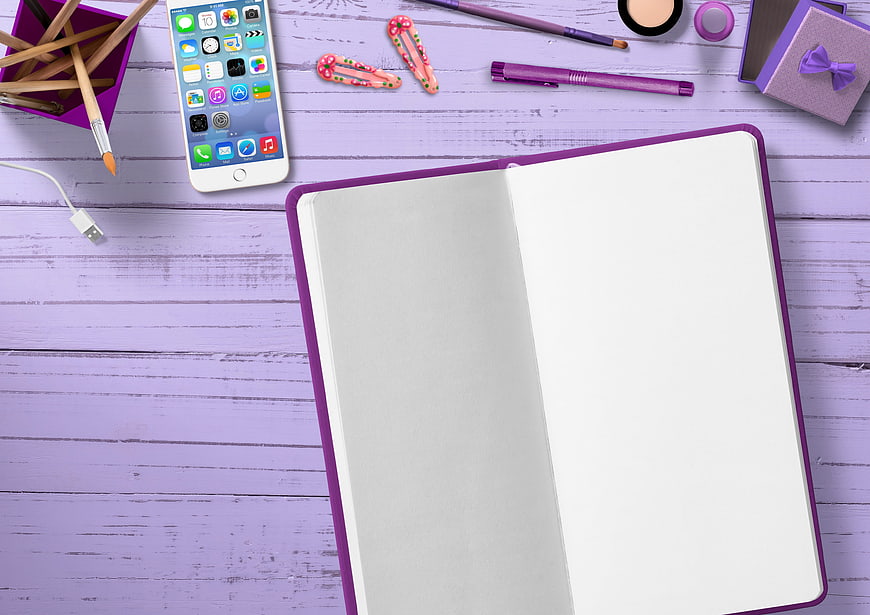 Purple flat lay with open notebook, smartphone, and stationery on wooden desk