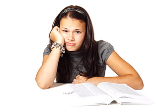 Bored teenage girl resting head on hand while studying with open book