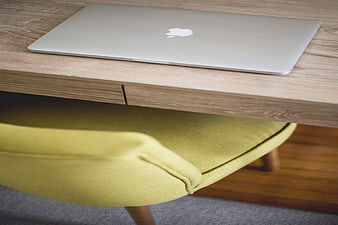 Closed MacBook on Wooden Desk with Yellow Chair