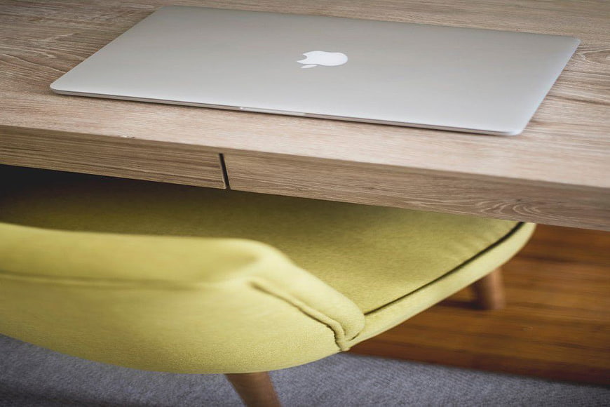 Closed MacBook on Wooden Desk with Yellow Chair