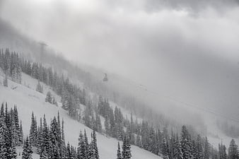 Snowy mountain landscape with cable car in fog