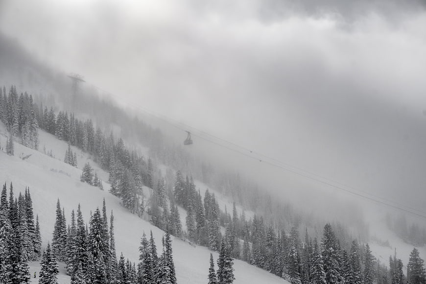 Snowy mountain landscape with cable car in fog