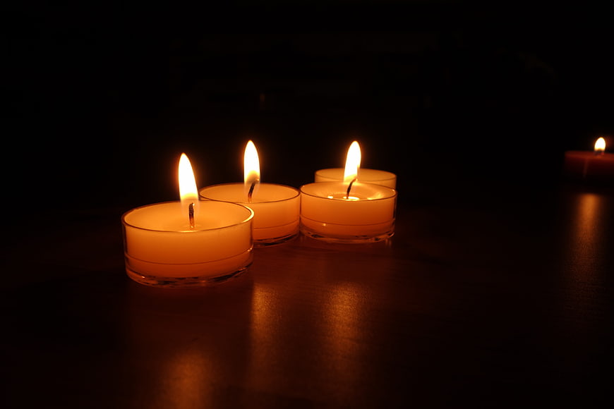 Glowing Tea Light Candles on Dark Wooden Surface