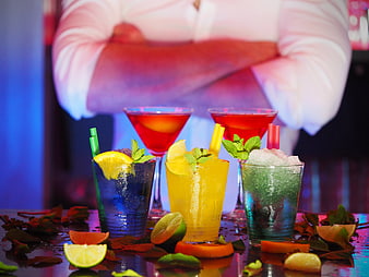 Colorful cocktails on bar counter with bartender background