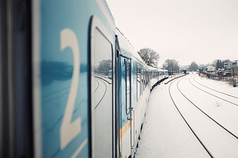 Blue train on snowy tracks in winter