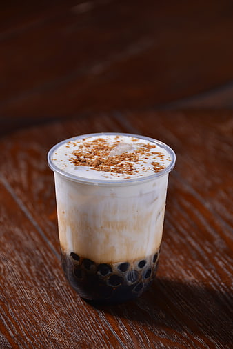 Iced Brown Sugar Pearl Milk Tea in Clear Plastic Cup on Wooden Table