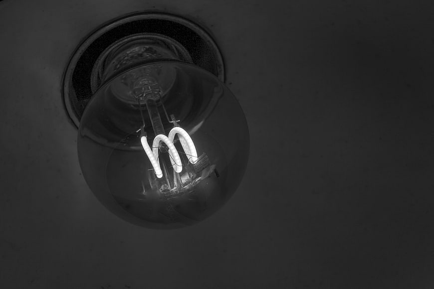 Black and white low angle shot of glowing spiral CFL light bulb