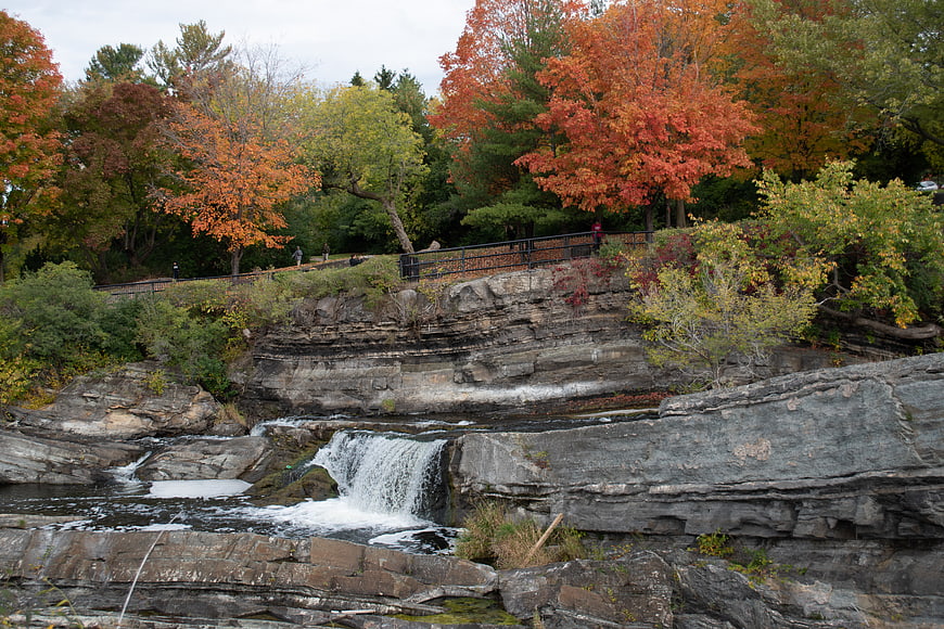 Autumn waterfall cascading over layered rocks with colorful foliage