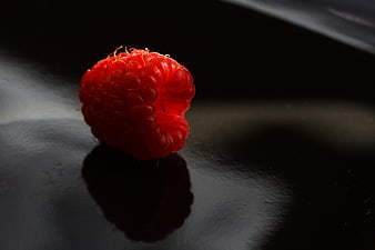 Single Red Raspberry on Dark Surface