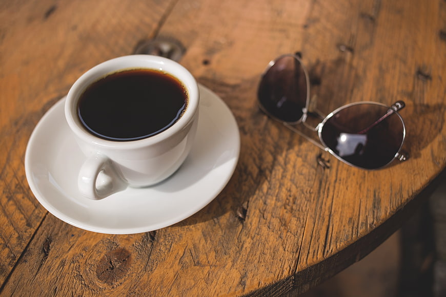 Espresso cup and sunglasses on rustic wooden table