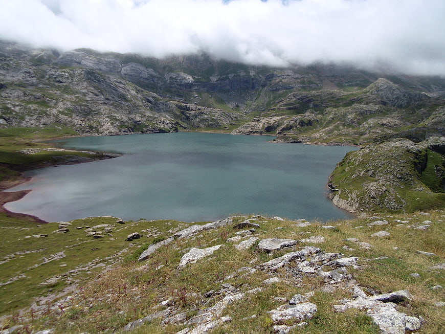 Serene Alpine Lake Surrounded by Rocky Mountains and Clouds