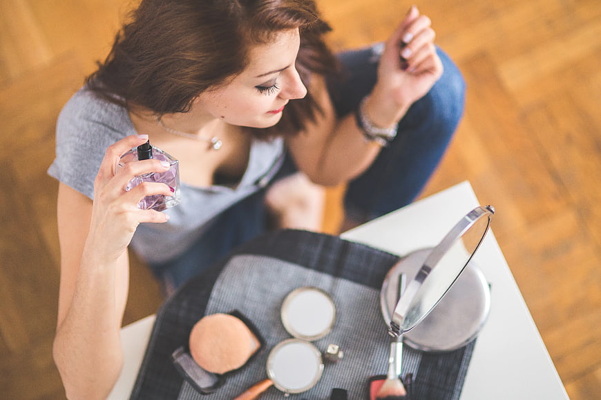 High angle view of young woman applying perfume with makeup