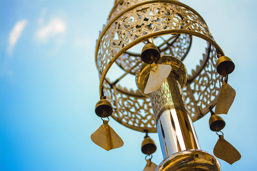 Golden ornate wind chime against blue sky